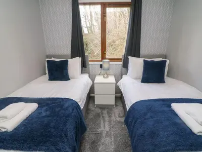 two twin beds in a room with a window at Park View Lodge, Arnside 7 in Carnforth
