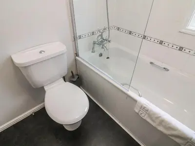 a white bathroom with a toilet and a bath tub at Park View Lodge, Arnside 7 in Carnforth