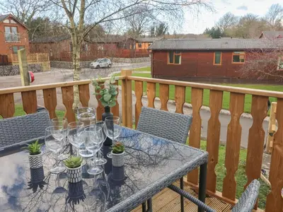 a table with glasses and plants on a balcony at Park View Lodge, Arnside 7 in Carnforth