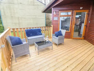 a wooden deck with two chairs and a table at Park View Lodge, Arnside 7 in Carnforth