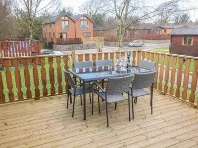 a table and chairs on a wooden deck at Park View Lodge, Arnside 7 in Carnforth