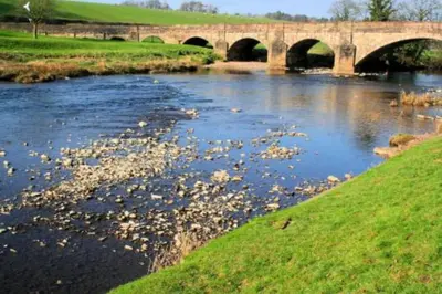 a river with a bridge in the background at Cosy 19th century town-house in Clitheroe