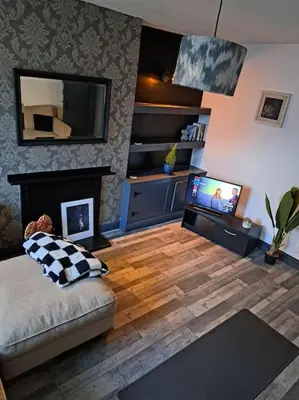 a living room with a couch and a television and a fireplace at Cosy 19th century town-house in Clitheroe
