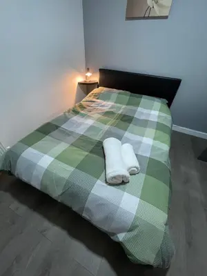 a green and white bed with two towels on it at Galway Suite in Preston