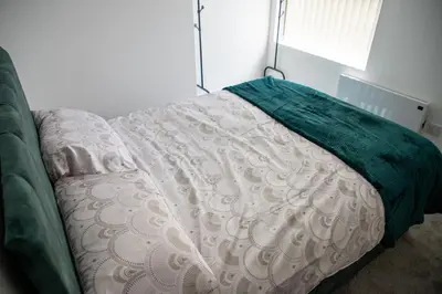 a bed with a green blanket on top of it at Balmoral Stays 5 - Second Floor in Blackpool
