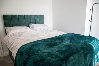 a bed with a green blanket on top of it at Balmoral Stays 5 - Second Floor in Blackpool