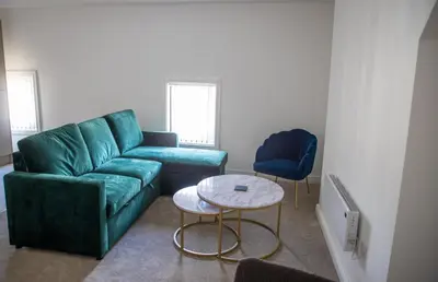 a living room with a green couch and two chairs at Balmoral Stays 5 - Second Floor in Blackpool