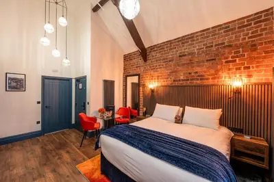 a bedroom with a bed and a brick wall at The Old Lyric Hall - A St David Aparthotel in Barrow in Furness