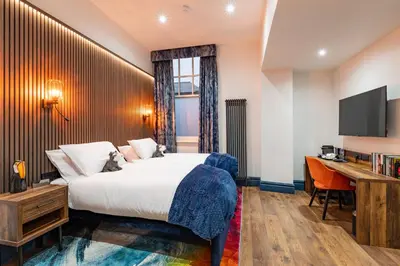 a bedroom with a bed and a desk and a television at The Old Lyric Hall - A St David Aparthotel in Barrow in Furness