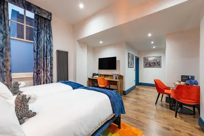 a hotel room with two beds and a desk and a tv at The Old Lyric Hall - A St David Aparthotel in Barrow in Furness