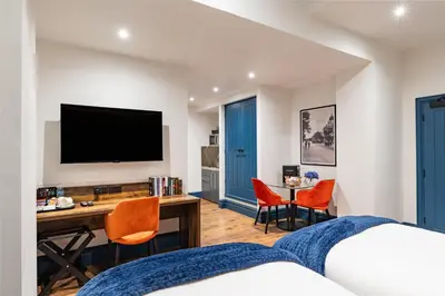 a bedroom with a bed and a desk with a television at The Old Lyric Hall - A St David Aparthotel in Barrow in Furness