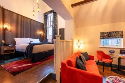 a bedroom with a bed and a red couch at The Old Lyric Hall - A St David Aparthotel in Barrow in Furness