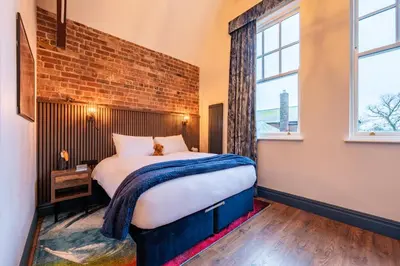 a bedroom with a bed and a brick wall at The Old Lyric Hall - A St David Aparthotel in Barrow in Furness