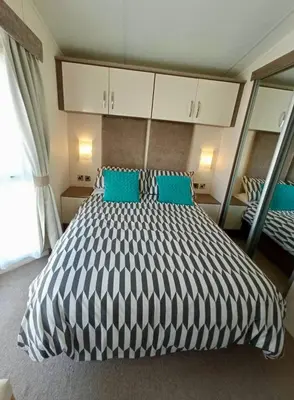 a bedroom with a large bed with blue pillows at Sandpiper Port Haverigg Marina in Millom