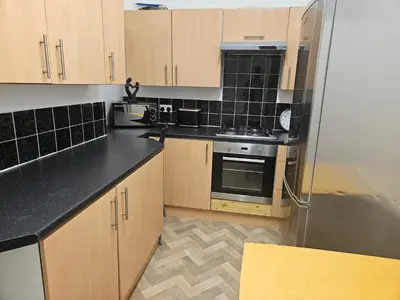 a kitchen with wooden cabinets and a stainless steel refrigerator at Liverpool Haven, Stylish and Spacious 3-Bedroom Apartment with City Access in Liverpool