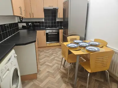 a small kitchen with a table and chairs and a dishwasher at Liverpool Haven, Stylish and Spacious 3-Bedroom Apartment with City Access in Liverpool