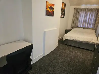 a small room with two beds and a tv at Liverpool Haven, Stylish and Spacious 3-Bedroom Apartment with City Access in Liverpool
