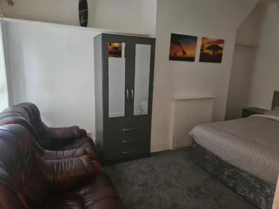 a bedroom with a couch and a dresser and a bed at Liverpool Haven, Stylish and Spacious 3-Bedroom Apartment with City Access in Liverpool