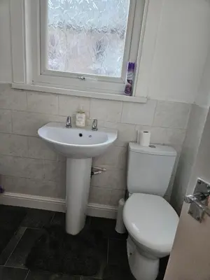 a bathroom with a toilet and a sink and a window at Liverpool Haven, Stylish and Spacious 3-Bedroom Apartment with City Access in Liverpool