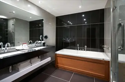 a bathroom with a tub and two sinks and a mirror at DoubleTree by Hilton Hotel & Spa Liverpool in Liverpool