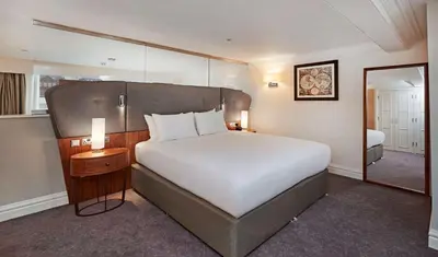 a bedroom with a large bed and a mirror at DoubleTree by Hilton Hotel & Spa Liverpool in Liverpool