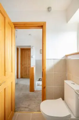 a bathroom with a white toilet and a hallway at Bright Double Room l Smart TV l 5 Minute Walk from Train Station in Egerton
