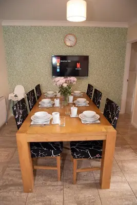 a wooden dining room table with chairs and a tv at Highcross Corner in Poulton le Fylde
