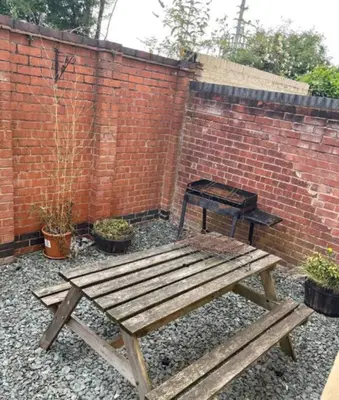 a wooden bench and a table in front of a brick wall at Vibrant Artist Hideaway by Centre Parking in Liverpool