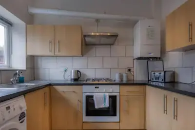 a kitchen with wooden cabinets and a stove top oven at Vibrant Artist Hideaway by Centre Parking in Liverpool