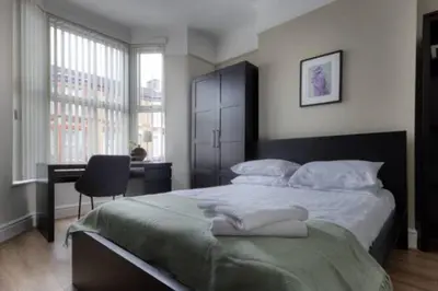 a bedroom with a large bed with a chair and a desk at Vibrant Artist Hideaway by Centre Parking in Liverpool