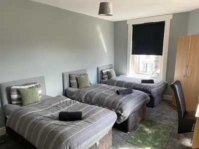 a room with two beds and a flat screen tv at The Clifton Guest House in Liverpool