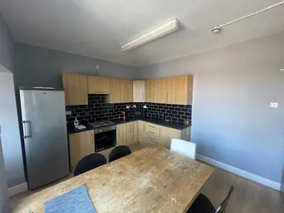 a kitchen with a wooden table and a refrigerator at The Clifton Guest House in Liverpool