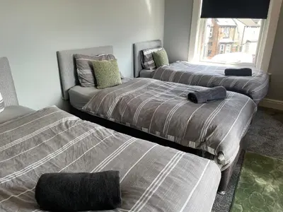 a bedroom with two beds and a couch in it at The Clifton Guest House in Liverpool