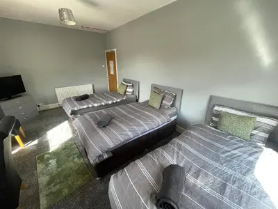 a room with two beds and a tv in it at The Clifton Guest House in Liverpool