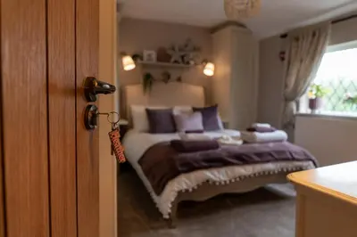a bedroom with a bed with purple pillows at Heather room at field view cottage in Eccleston