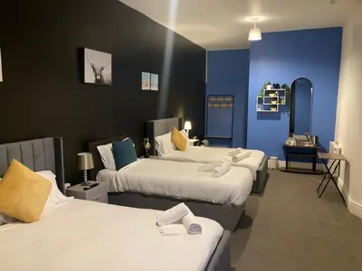 a room with three beds with blue walls at North Coast Hotel in Blackpool