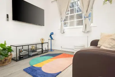 a living room with a television and a colorful rug at Stylish Prime Location Apartment by VICHY in Liverpool