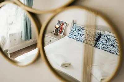 a mirror reflection of a bed with blue and white pillows at Stylish Prime Location Apartment by VICHY in Liverpool