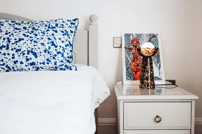 a bed with a blue and white pillow and a nightstand at Stylish Prime Location Apartment by VICHY in Liverpool