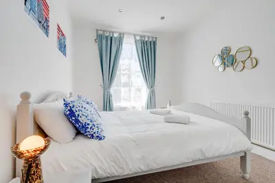 a white bedroom with a bed and a window at Stylish Prime Location Apartment by VICHY in Liverpool