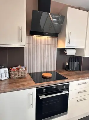 a kitchen with a black stove and white cabinets at Everythings Cosy at Clucas in Ormskirk