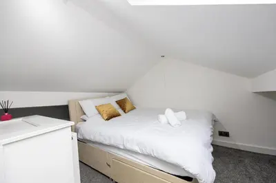 a bedroom with a bed with white sheets and gold pillows at Manor Terrace Retreat in Accrington