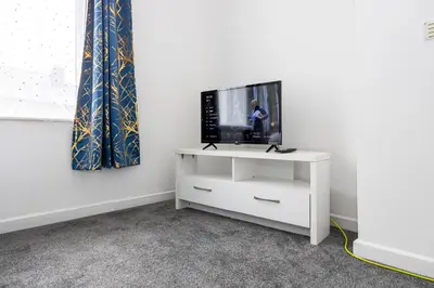 a tv sitting on a white stand in a room at Manor Terrace Retreat in Accrington