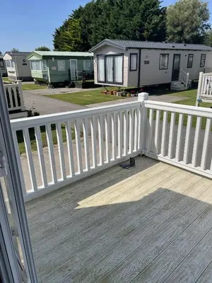 a white fence on a deck with some houses at The Thimble static Holiday Home in Lancaster