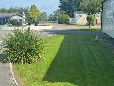 a yard with green grass and a house at The Thimble static Holiday Home in Lancaster