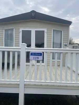 a house with a sign on a white fence at The Thimble static Holiday Home in Lancaster