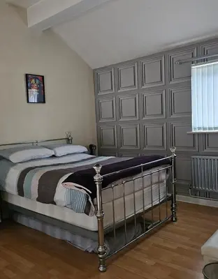 a bedroom with a bed with a large gray headboard at Open planned apartment in Birkenhead