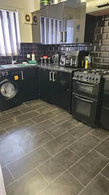 a kitchen with a stove and a washing machine at Open planned apartment in Birkenhead