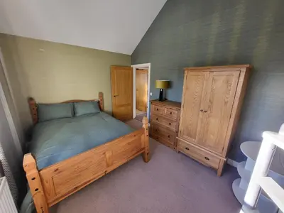 a bedroom with a wooden bed and a dresser at Anchor Gardens Villa in Lindal in Furness