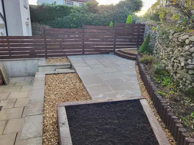 a garden with a wooden fence and a patio at Anchor Gardens Villa in Lindal in Furness